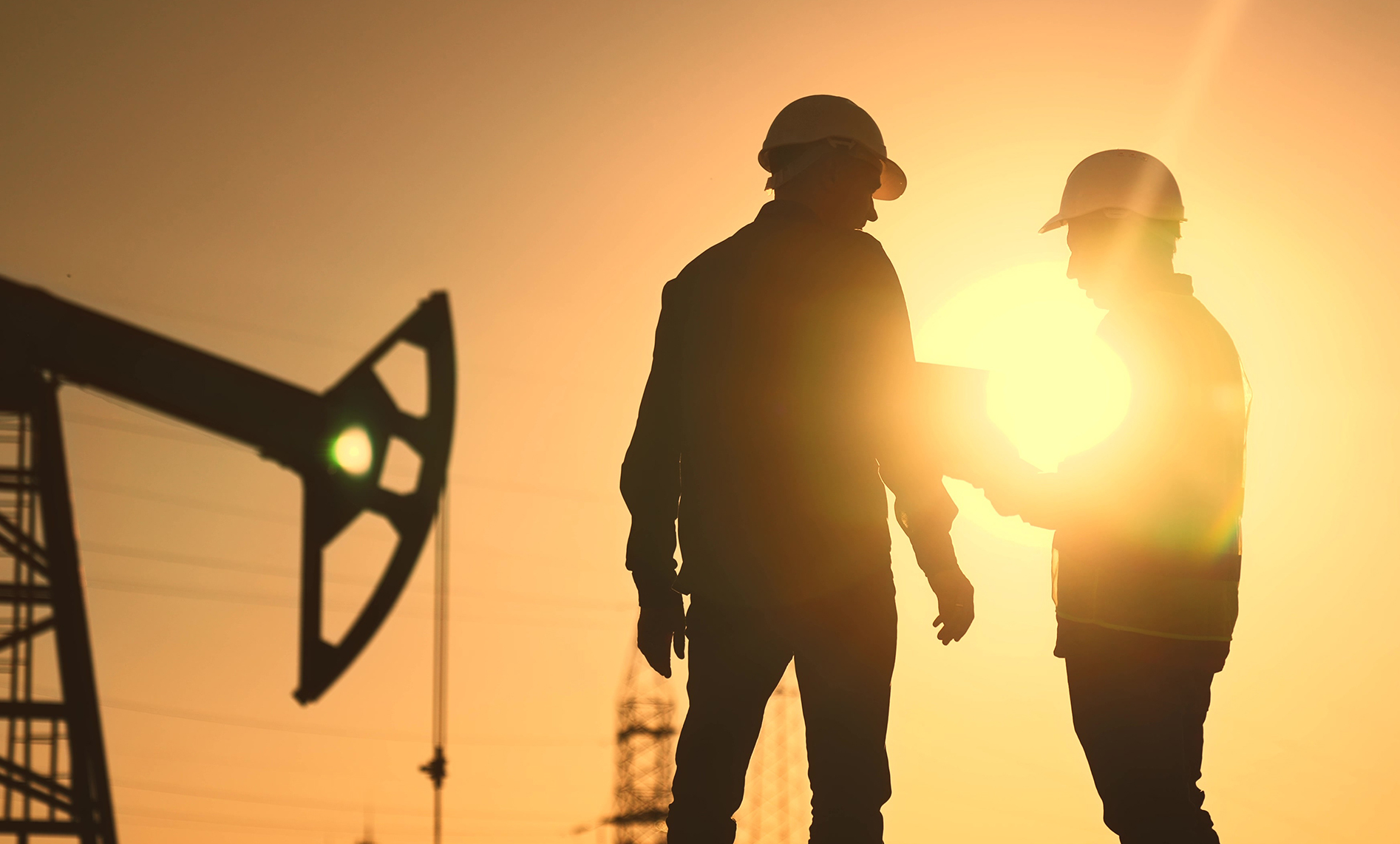 two men stadning near oil derrick